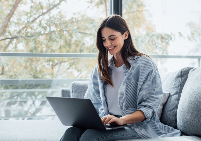 Frau sitzt am Laptop vor einem Fenster