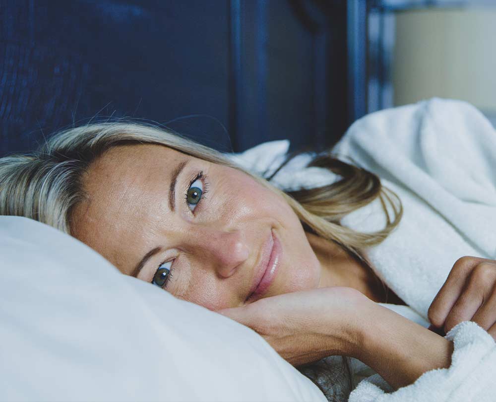 Schnellere Wirkung von Schmerztabletten beitragsbild: frau liegt auf dem bett