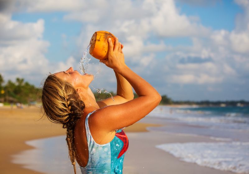 Frau trinkt Kokoswasser am Meer