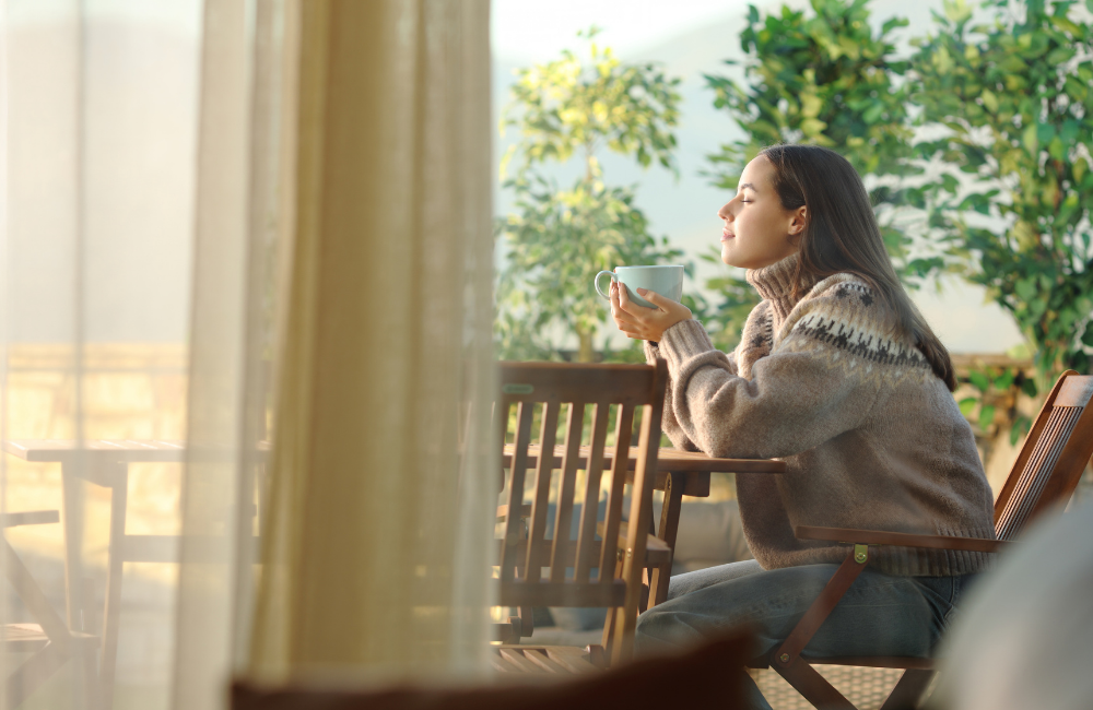 Entschleunigung im Alltag Beitragsbild: Frau sitz mit Teetasse auf der Terasse