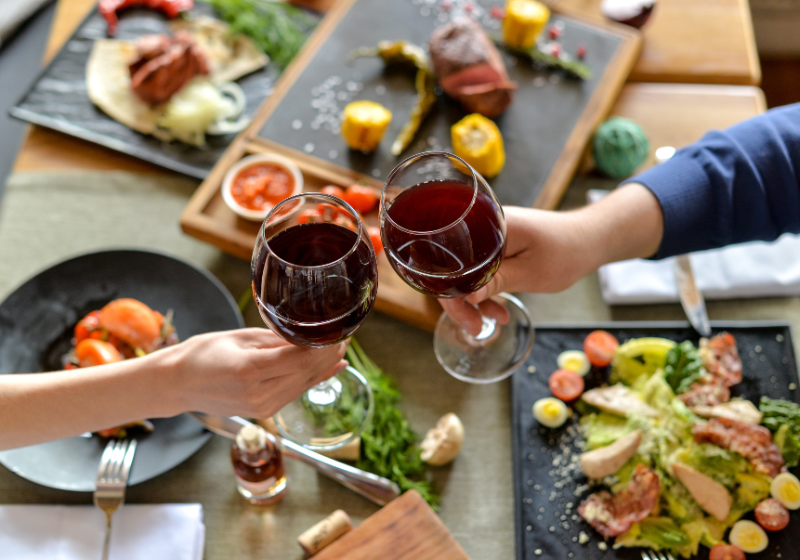 Anstoßen mit Rotwein über einem Essen