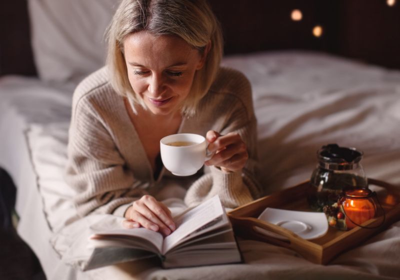 frau liest mit tasse tee im bett