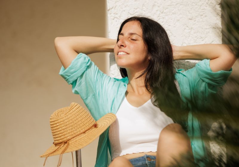 Frau mit grüner langer Bluse und Sonnenhut zum Schutz gegen die Sonne