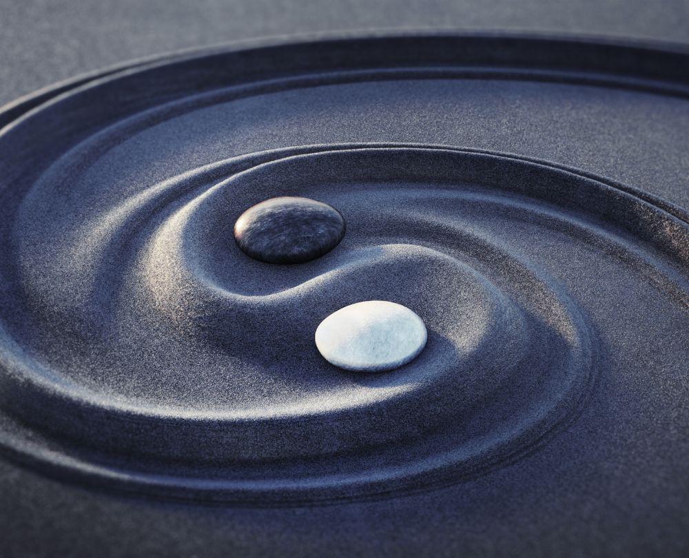 TCM-Ernährung Wie traditionelle chinesische Ernährung Körper und Psyche beeinflusst Beitragsbild, Bild von schwarzem und weißen Stein im schwarzen Sand die Yin Yang Symbol nachbilden