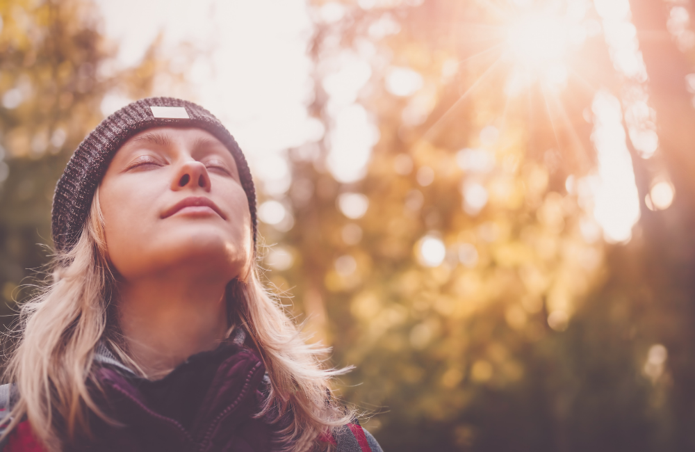 Wie Stress unsere Gesundheit beeinflusst beitragsbild - frau atmet im wald durch